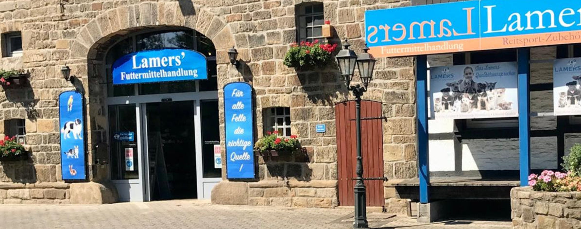 Außenansicht der Lamers Futtermittelhandlung in Schwerte mit blauen Werbeschildern am Eingang